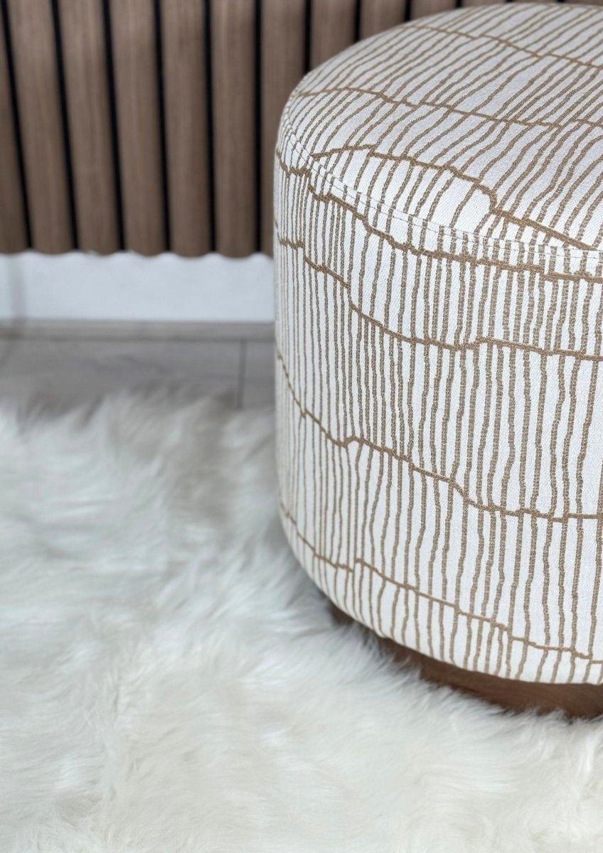 "Decorative pouf with linear stitched top and brown fabric foundation"
