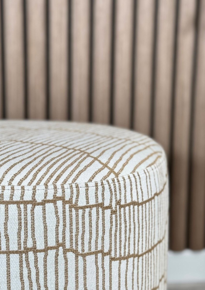 "Contemporary designer ottoman with linear fabric design and brown base"