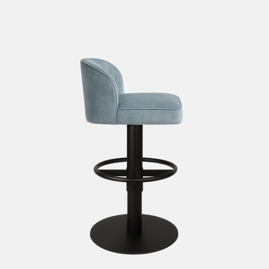 Light blue upholstered bar stool with curved backrest, vertical stitching, and black pedestal base with circular footrest.