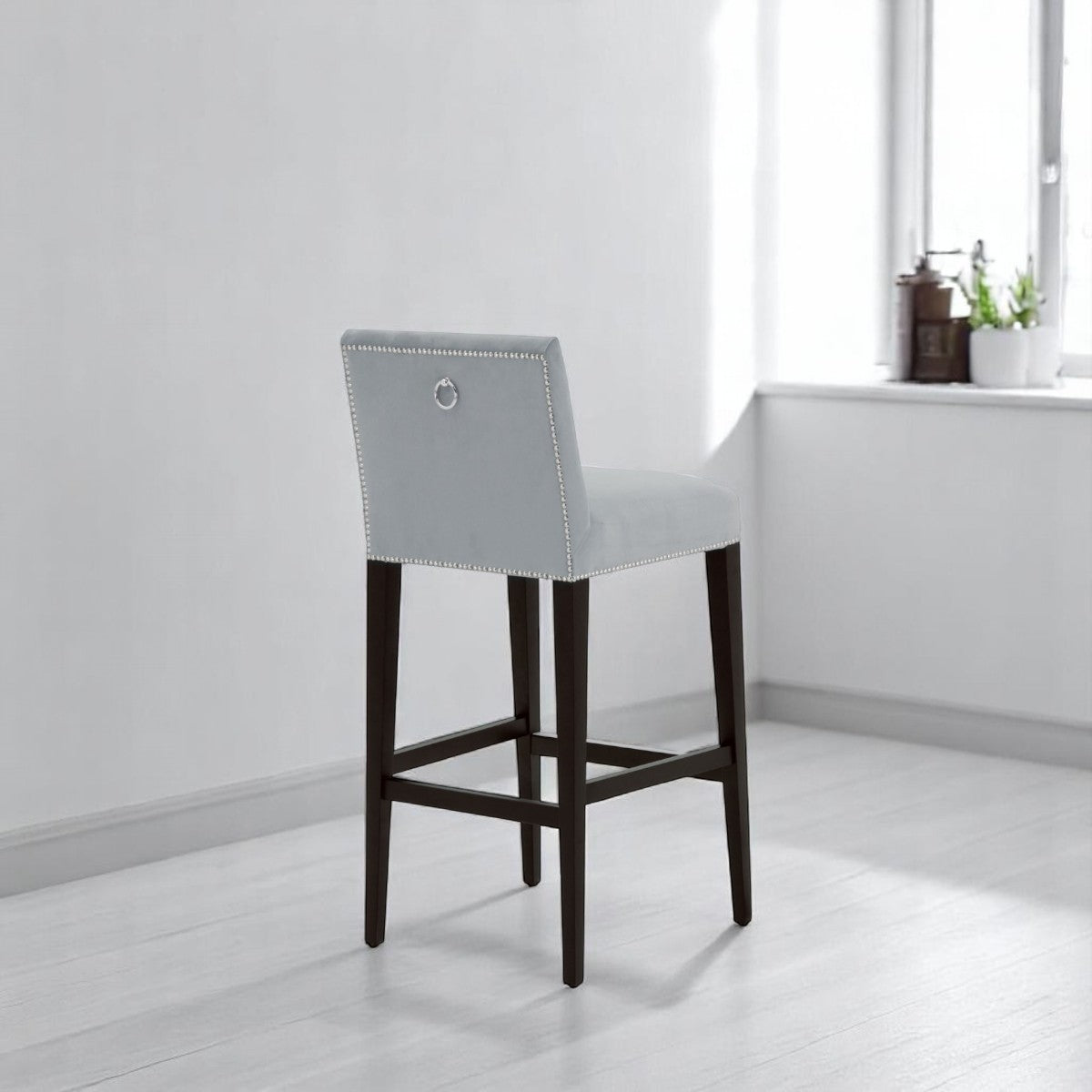 alt="Contemporary velvet bar stool with square cushion, black wood legs, and polished chrome leg rest"