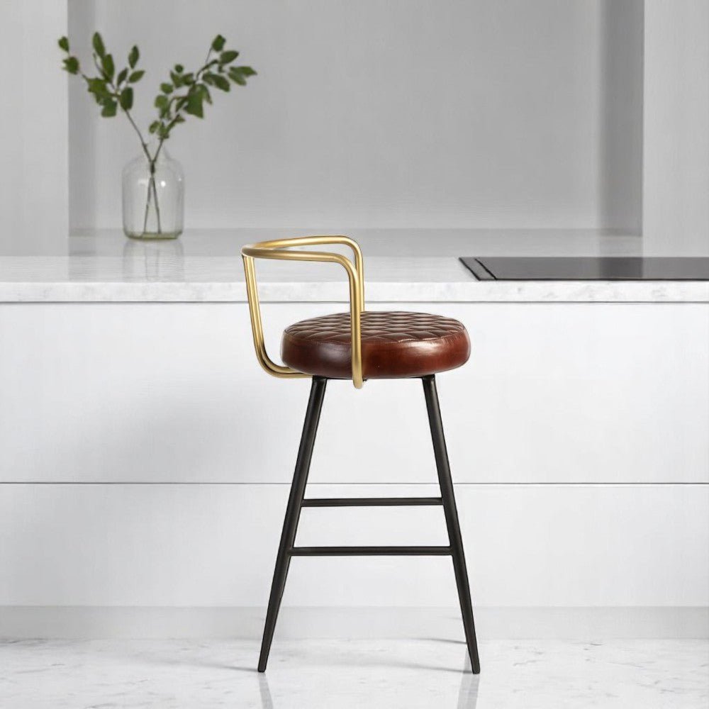 alt="Modern bar stool featuring diamond-stitched leather seat, gold accent back, and black metal base"