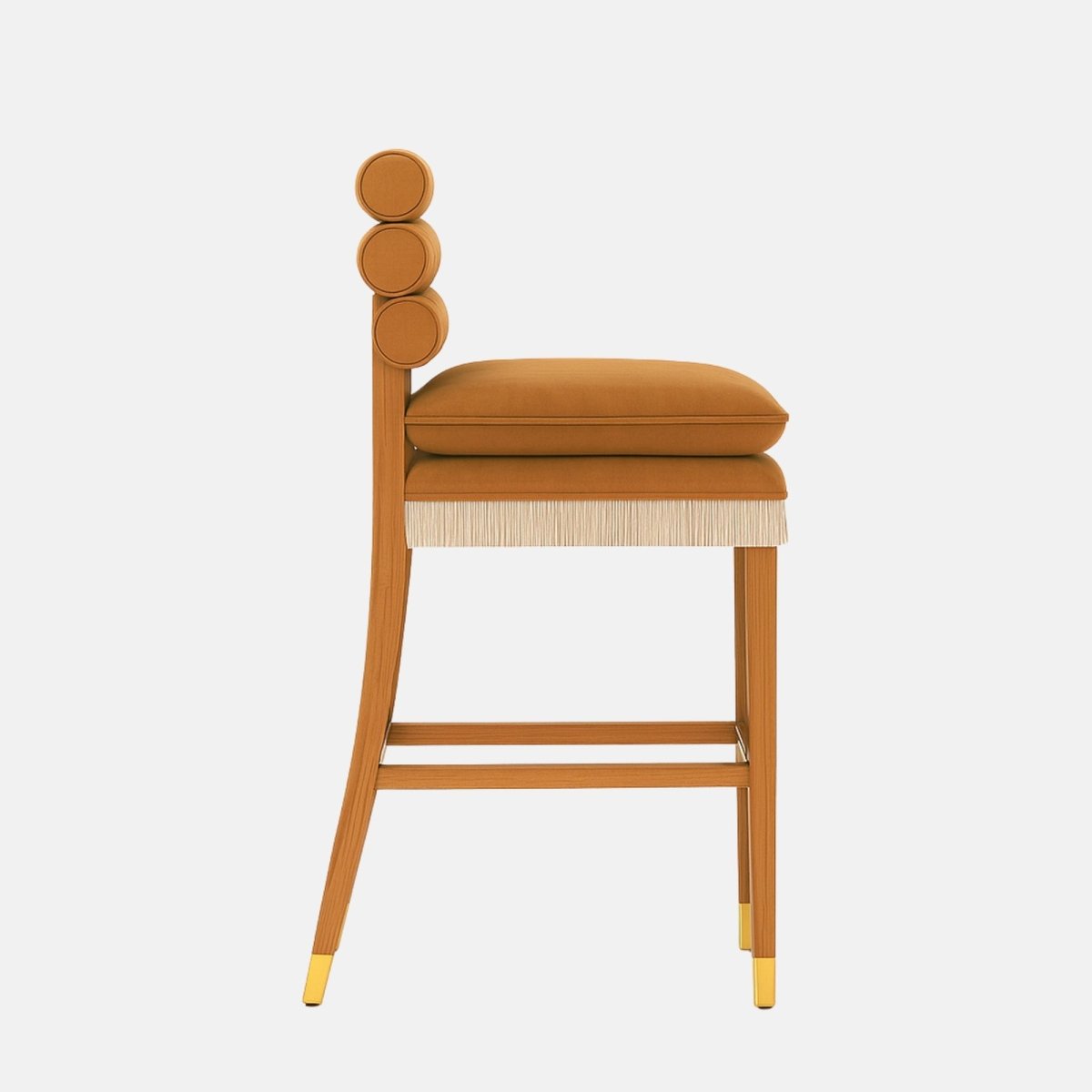 Side view of a tan upholstered bar stool with a double seat cushion, fringe trim beneath the seat, a slim wooden frame with footrest, brass-capped legs, and three stacked round padded backrests on a white background.