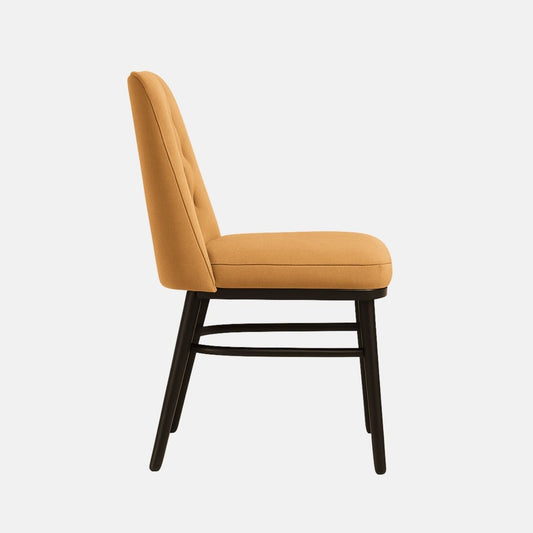 A mid-century modern dining chair with a deep-button tufted backrest and cushioned seat, both upholstered in sandy beige velvet. The chair features sleek, straight black wooden legs and a minimalist support frame, combining comfort with elegant simplicity.