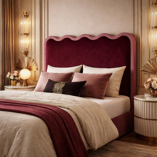Luxurious bedroom with a deep red scalloped upholstered headboard, styled with layered bedding, decorative pillows, and elegant gold-accented bedside tables and lighting.