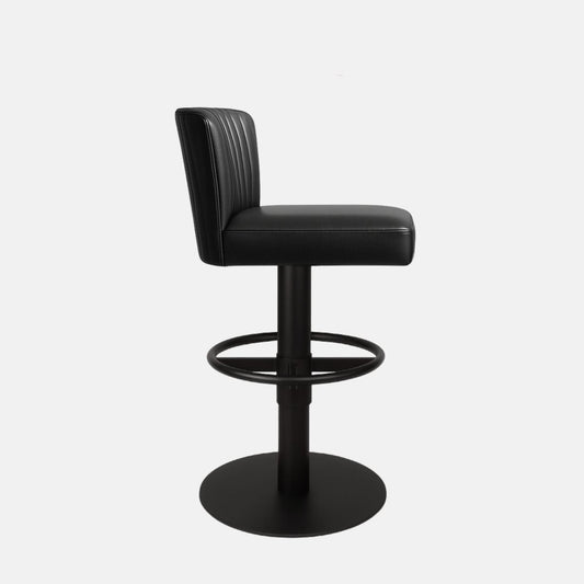 Side view of a black upholstered swivel counter stool with ribbed backrest, black pedestal base, circular footrest ring and round base on a white background.