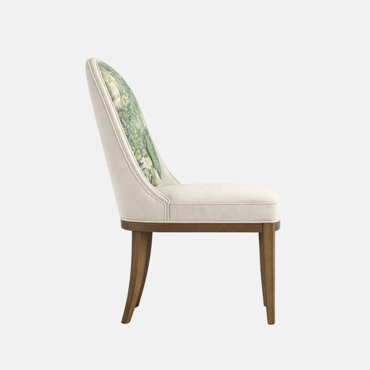 Upholstered accent chair with a cream fabric frame and cushioned seat, featuring a rounded backrest with a green botanical and bird-patterned fabric panel, supported by dark wooden legs, shown on a white background
