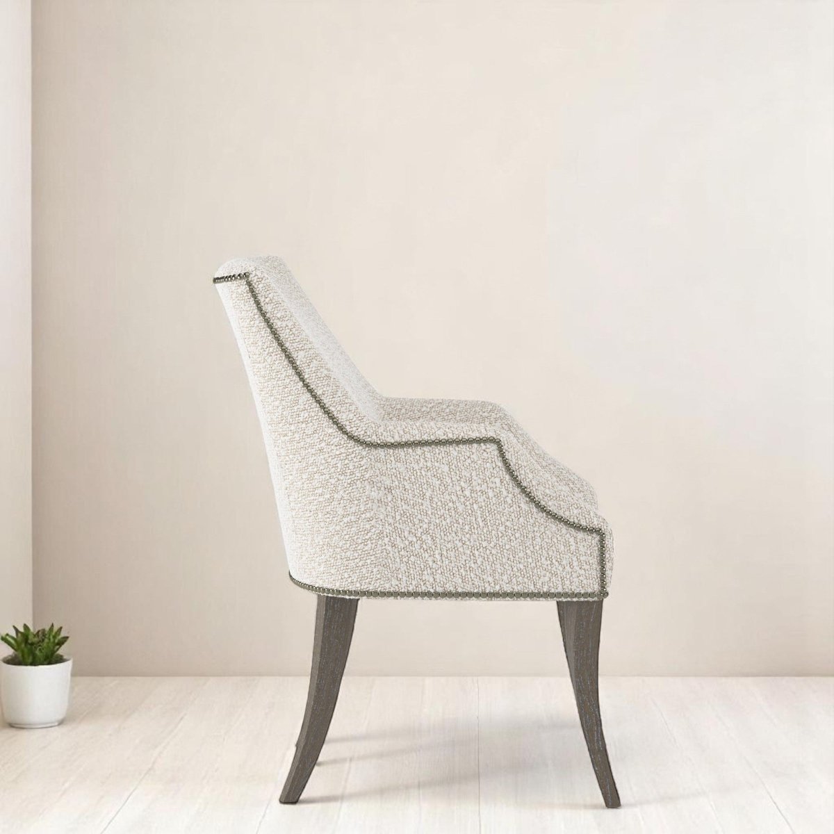 alt="Elegant natural-toned armchair featuring a curved profile and modern grey leg finish"