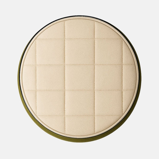 Two-tone round ottoman with olive green fabric body and cream quilted seat on black base modern upholstered stool for living room, bedroom, or hotel lounge.