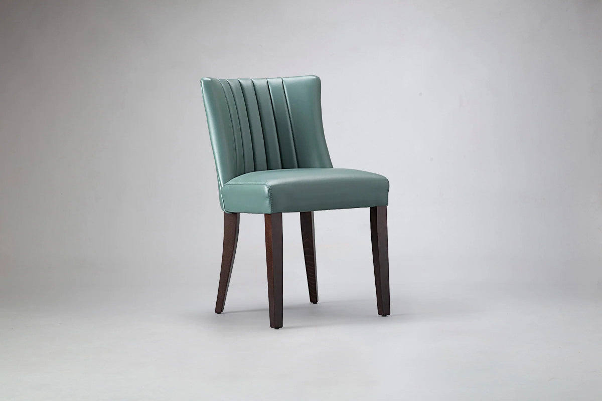 alt="Green dining chair with elegant flute back design, soft leather upholstery, and black legs"