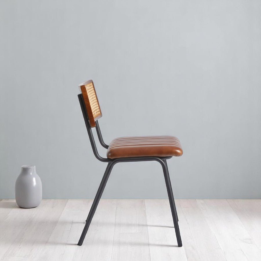 alt="Elegant rattan and leather chair with black metal legs and detailed stitched seat"