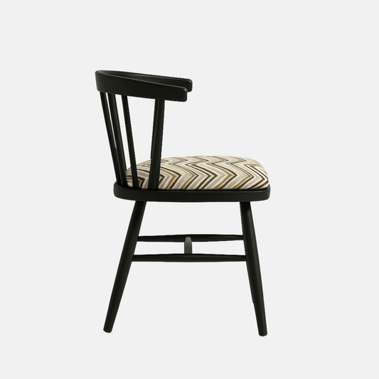 A modern black Windsor-style chair with a curved spindle backrest and four angled legs, featuring a cushioned seat upholstered in a geometric zigzag fabric with neutral tones. The chair is photographed against a light beige background with soft shadows for a clean, realistic presentation.