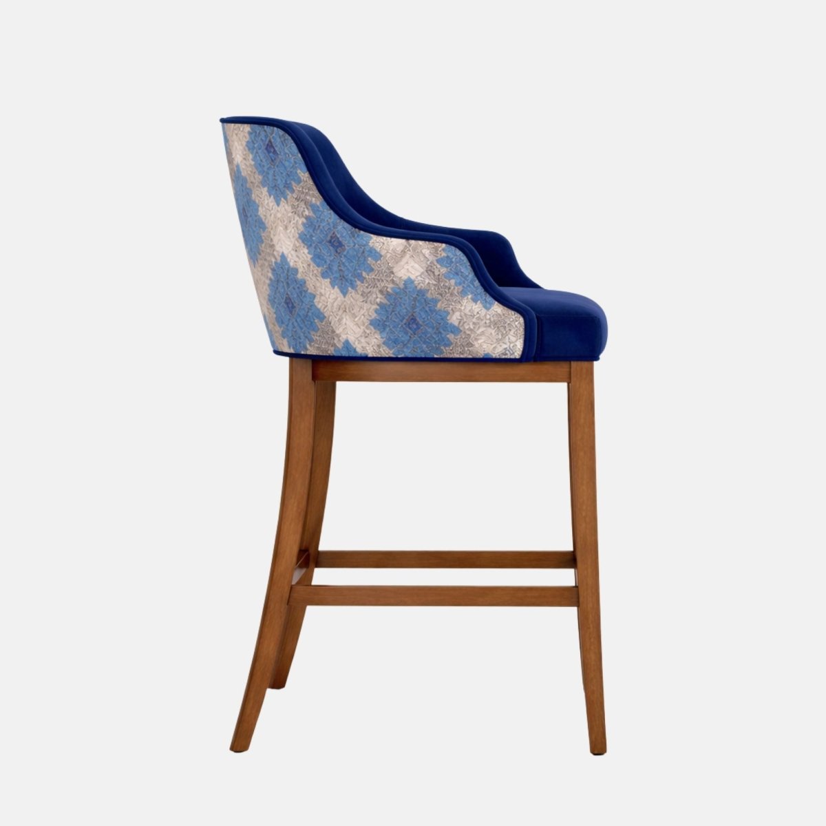 Front angled view of a bar-height stool with a navy upholstered seat and wraparound back/arms, patterned blue-and-cream fabric on the outer back panel, and a medium-brown wooden frame with four legs and a square footrest stretcher, photographed on a white background.