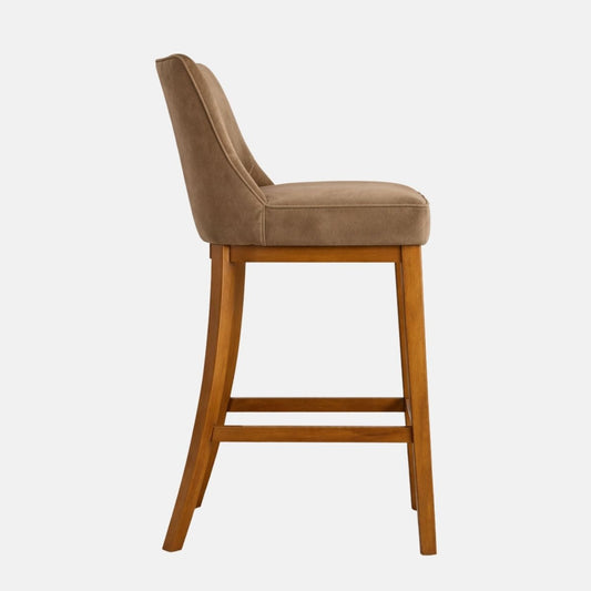 Side view of a brown upholstered bar stool with a curved backrest, thick padded seat, and tapered wooden legs with lower stretcher rails.