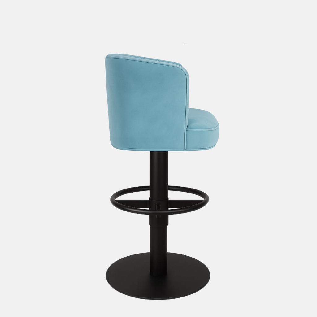 Light blue upholstered bar stool with a quilted backrest, circular black metal footrest, and round black base on a white background.