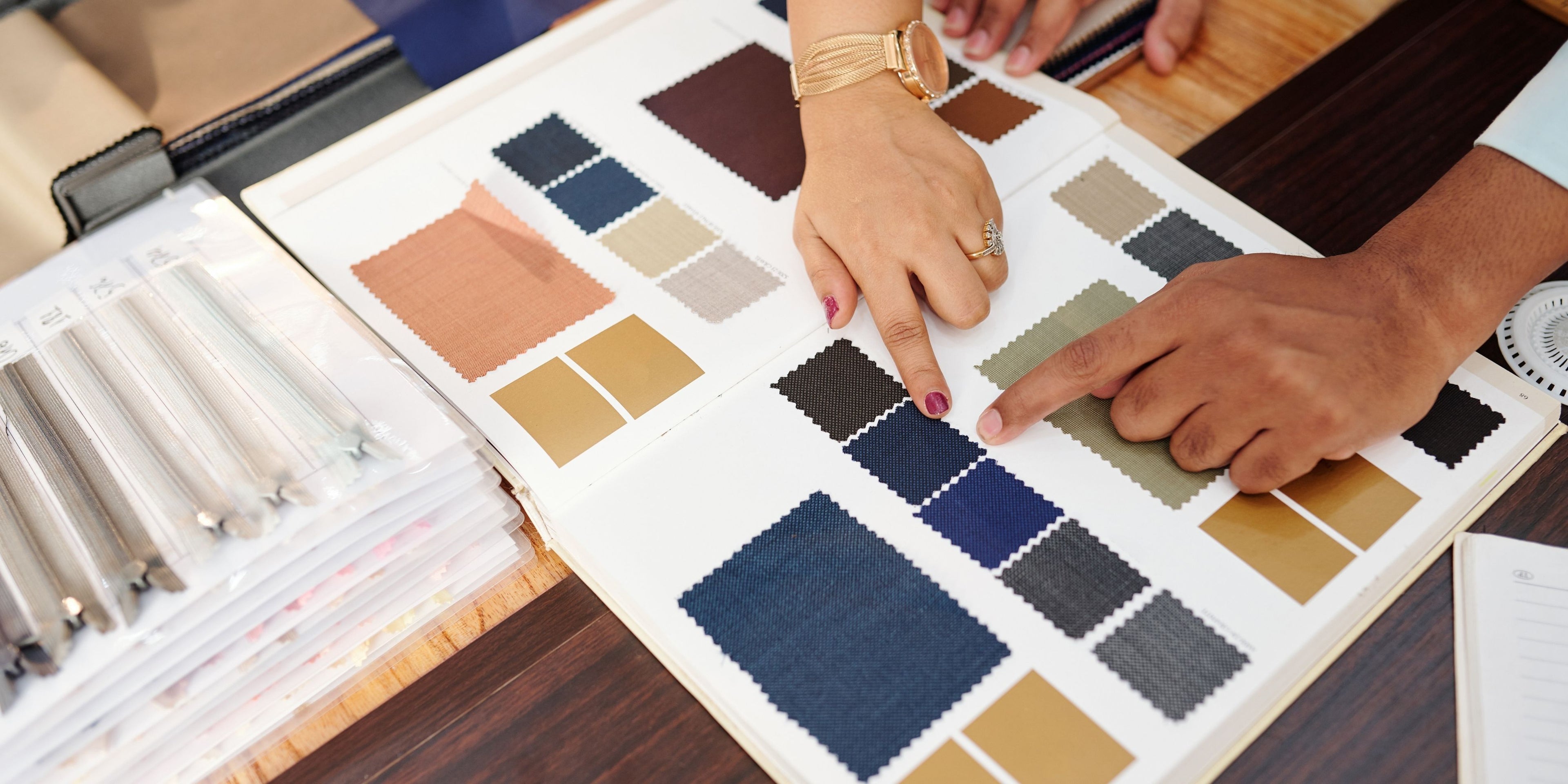 Hands choosing upholstery fabric swatches for bespoke dining chairs, lounge chairs, armchairs, and custom furniture.
