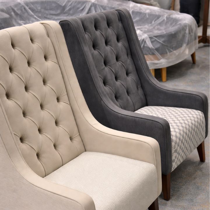 Elegant lounge chair with button tufted backrest and upholstered seat, featuring curved arms and wooden legs, ideal for hotels and hospitality interiors