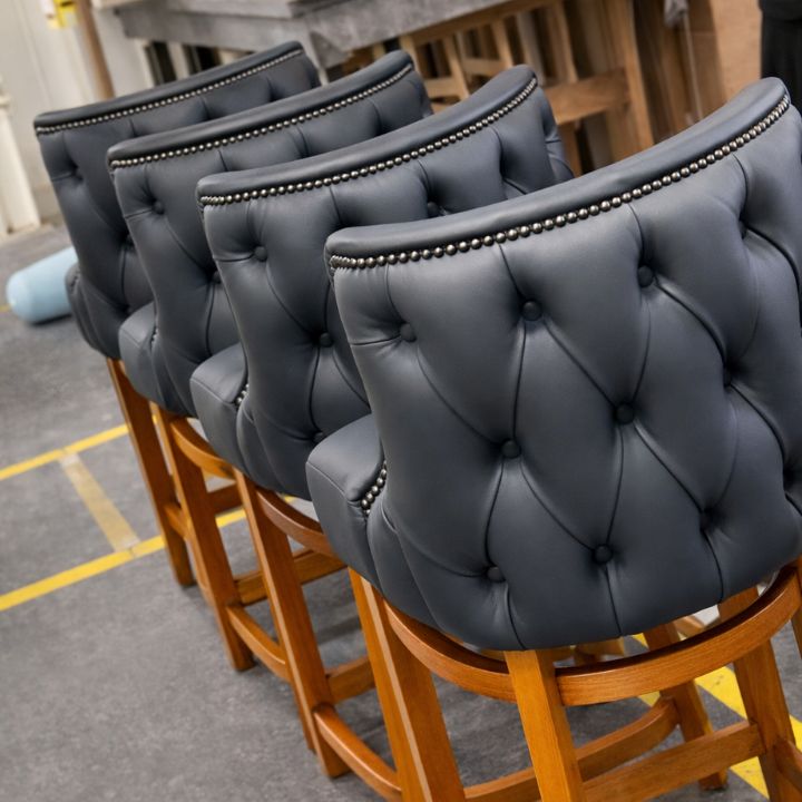 Elegant bar stool with black button tufted upholstery and studded trim, featuring wooden legs, ideal for bars and luxury hospitality interiors
