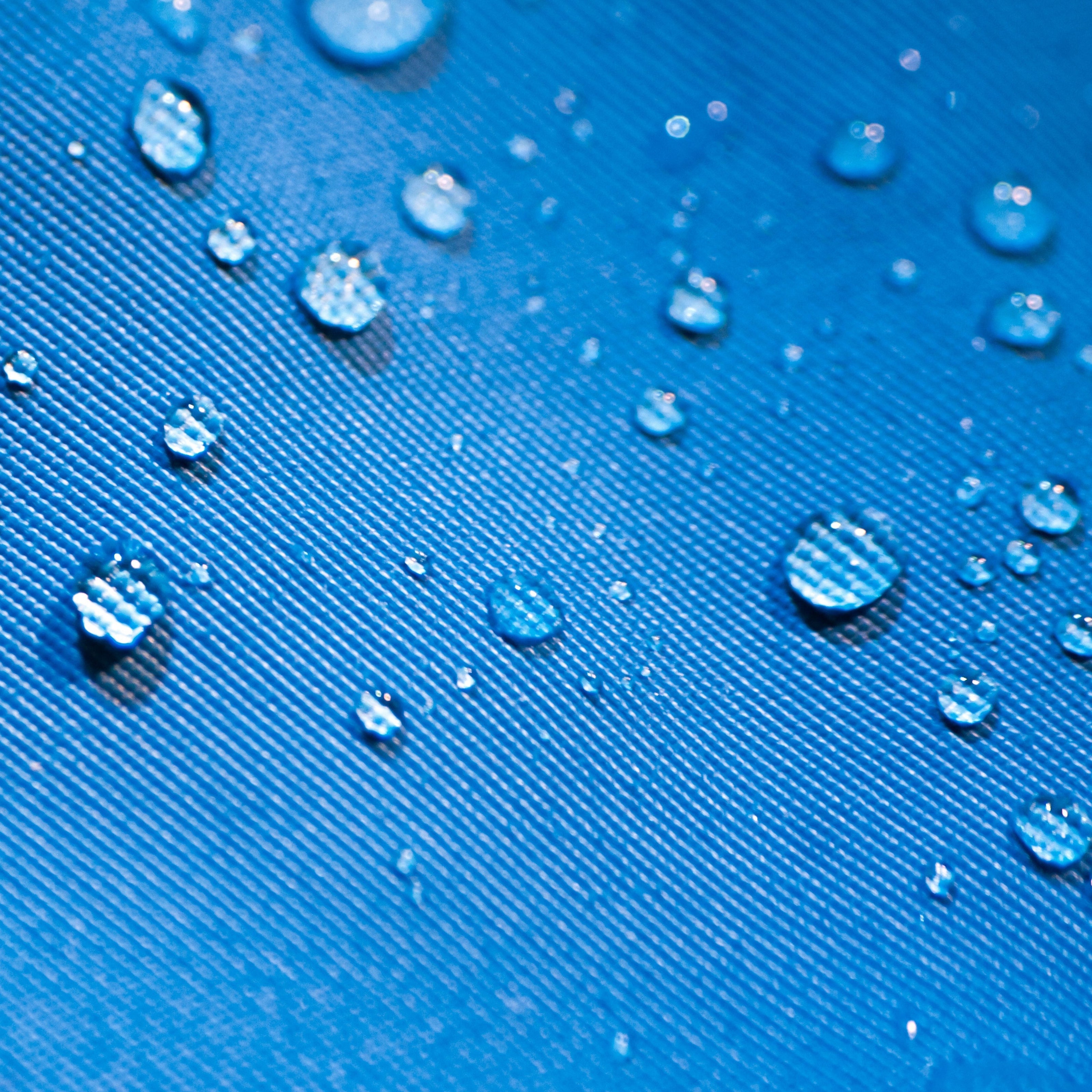 Close-up of water droplets beading on blue fabric, demonstrating waterproof or stain-resistant upholstery treatment for custom furniture.