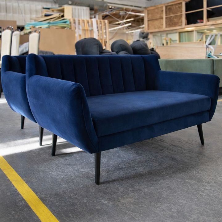 Contemporary blue velvet lounge armchair with curved arms, plush seat and wooden legs, ideal for hotel, lounge and hospitality interiors