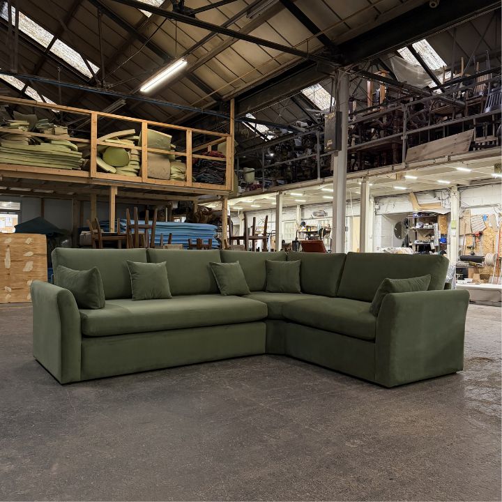 Large olive green upholstered corner sofa with cushions, modern sectional design ideal for lounges, hotels, and commercial interiors