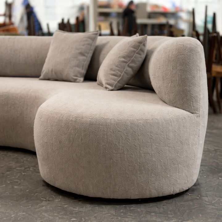 Modern curved sofa with soft bouclé upholstery and matching cushions, ideal for lounges, hotels, and contemporary interiors
