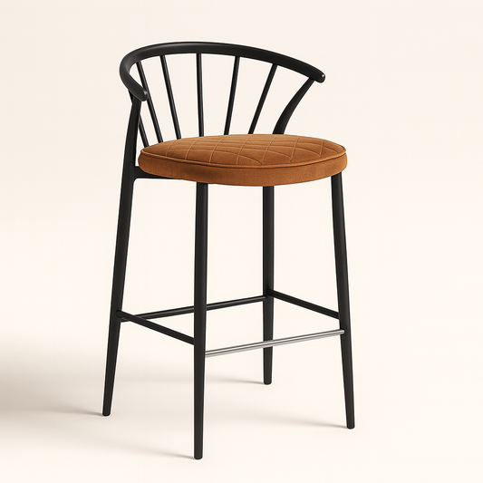 A modern bar stool featuring a matte black wooden frame with slender, tapered legs and a curved, open backrest supported by vertical spindles. The seat is upholstered in tan velvet with a diamond stitch pattern, adding a touch of texture and elegance. A sleek metal footrest completes the contemporary design.