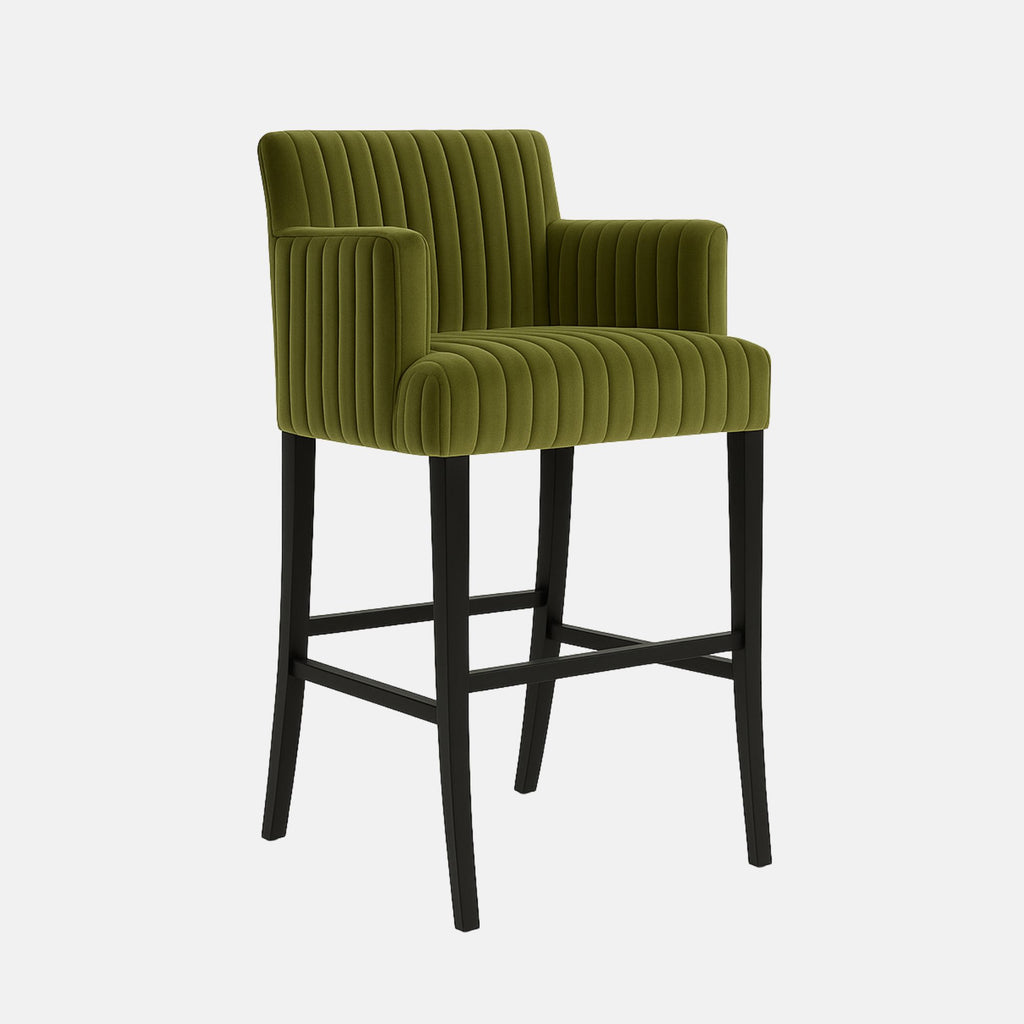 Olive green upholstered bar stool with vertical channel tufting, short armrests, and black wooden legs featuring footrests.