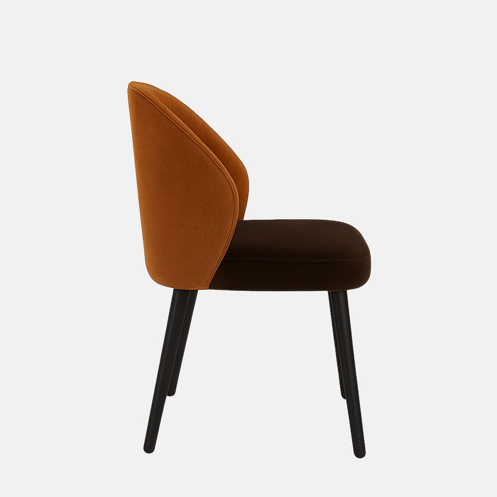 Modern upholstered chair with a curved backrest and vertical stitching. The backrest is covered in burnt orange fabric, while the seat cushion is dark brown. It has four black wooden legs and a minimalist, contemporary design