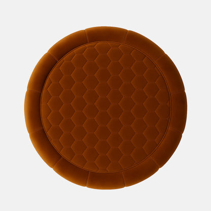 Rust velvet round ottoman with quilted top and vertical panel design on black base modern upholstered footstool or coffee table for living room or hotel lounge.