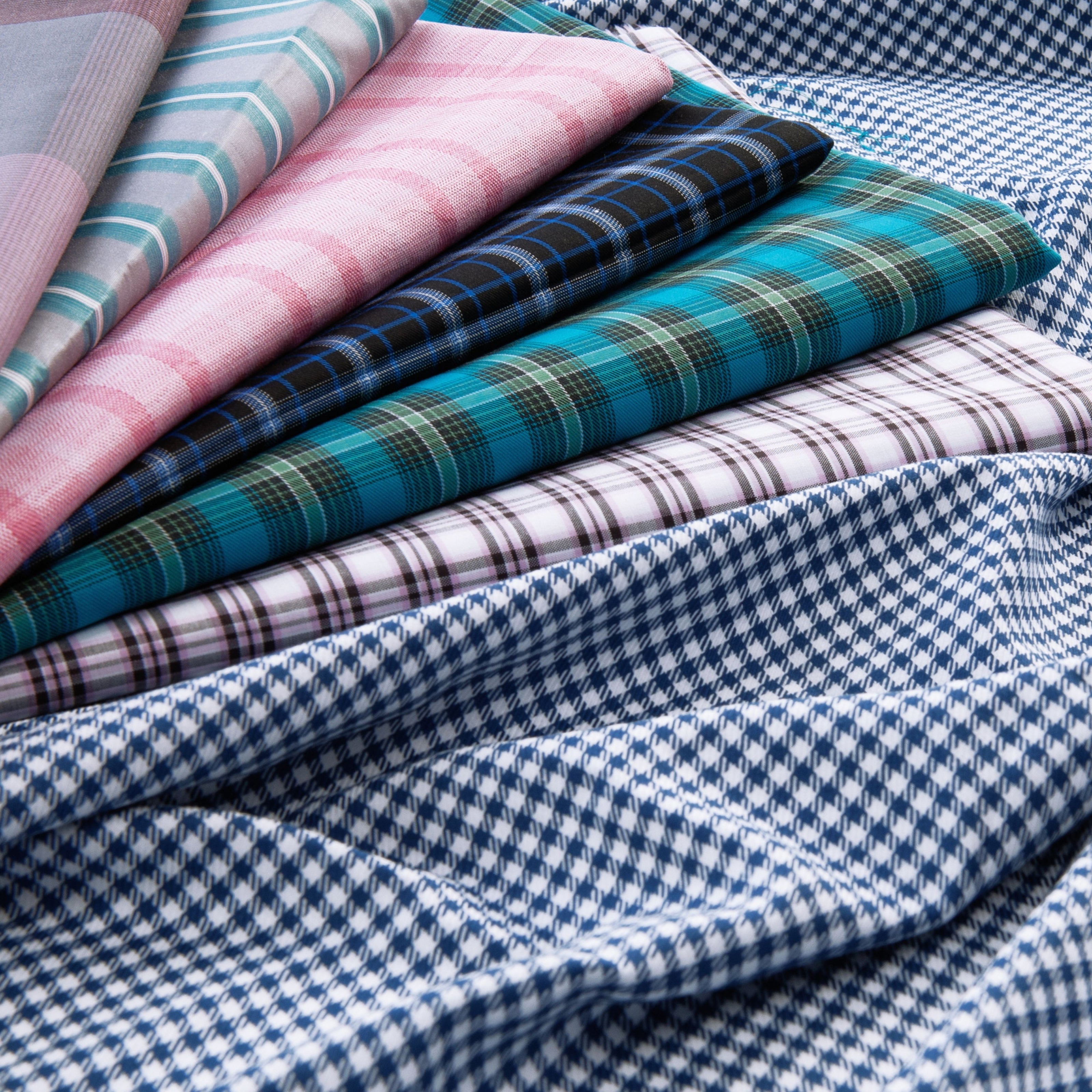 Stack of colourful checked and plaid fabrics in shades of blue, green, pink, and black, displayed for upholstery or custom furniture design.