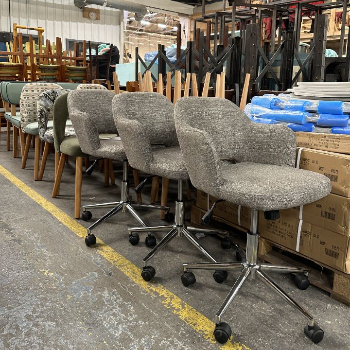 Modern upholstered dining chairs with swivel base and castor wheels, featuring textured fabric seats and chrome legs, suitable for hospitality and commercial use