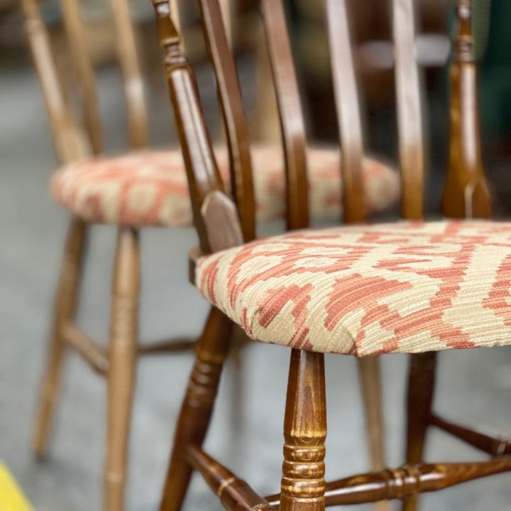 Wooden spindle back dining chairs with turned legs and patterned upholstered seats arranged in a showroom.