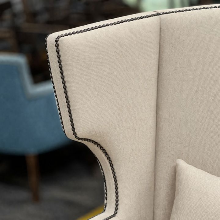 Close-up of cream upholstered booth seating with studded trim detail and soft fabric finish, ideal for restaurant and hospitality interiors
