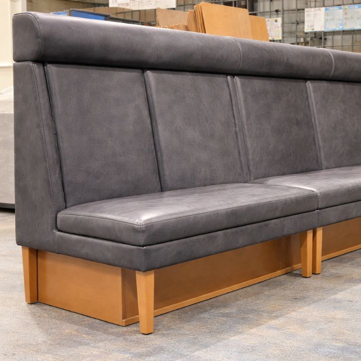 Modern booth seating with grey leather upholstery and wooden base, ideal for restaurants and hospitality interiors