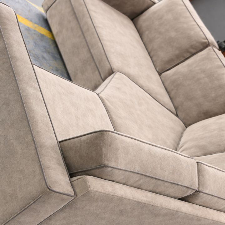 Close-up of modern upholstered sofa in neutral fabric with structured cushions and piping detail, ideal for lounges and hospitality interiors