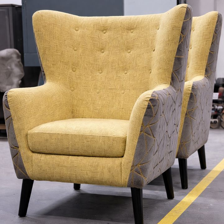 Stylish wingback lounge chair with yellow fabric upholstery, buttoned backrest and patterned side panels, ideal for hotels and modern interiors