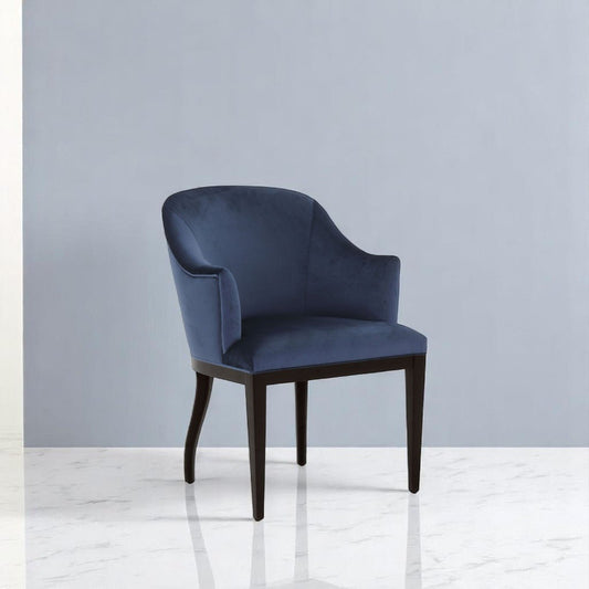 alt="Textured blue linen armchair with angled arms and dark wood legs on a neutral rug"