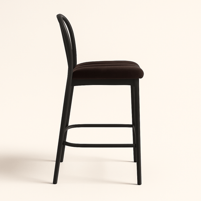 A modern bar stool featuring a matte black wooden frame with gently curved backrest slats, a sturdy metal footrest, and a plush dark chocolate brown velvet seat with vertical stripe stitching. The design combines elegance and comfort, suitable for contemporary kitchens or bars.