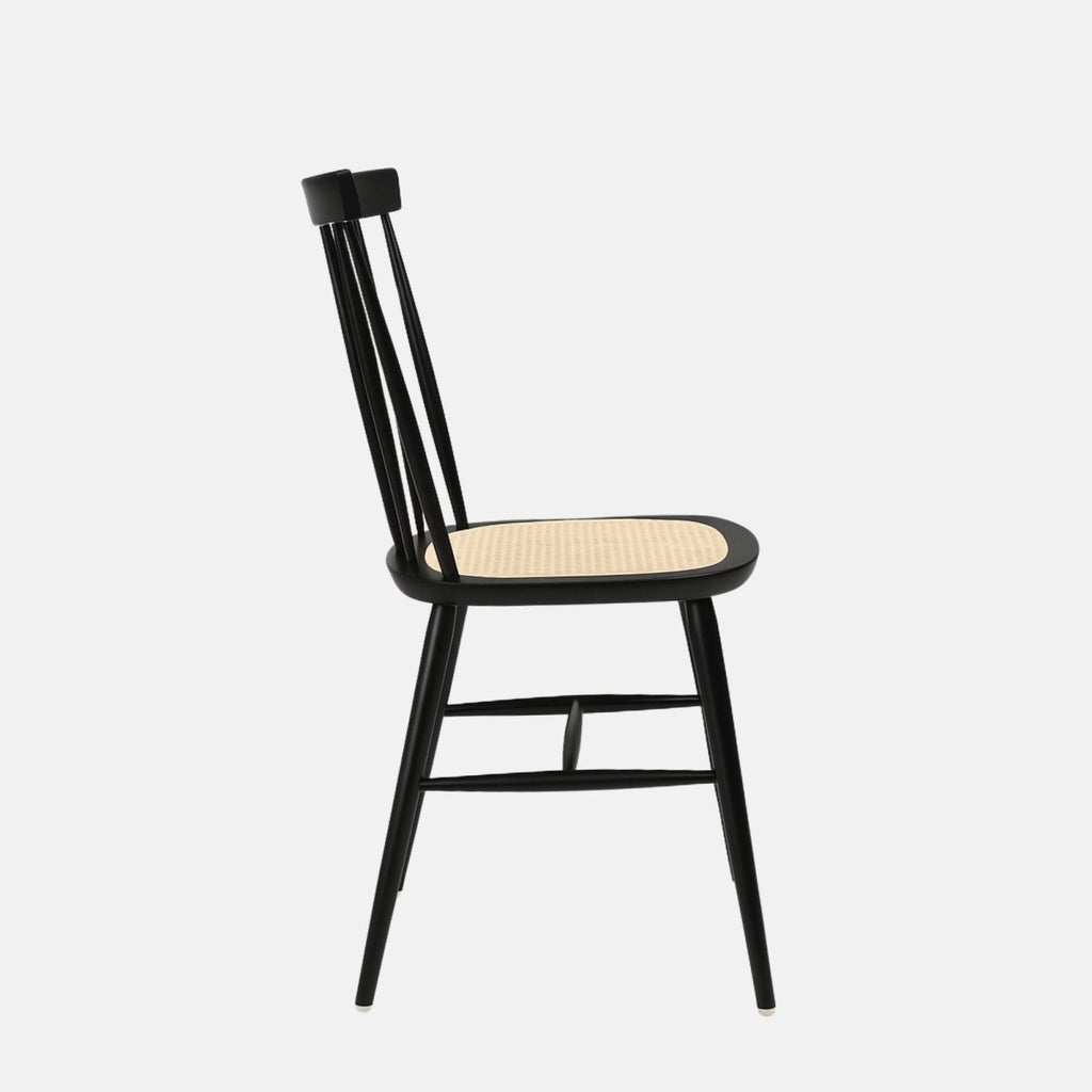 Black wooden dining chair with a spindle backrest and light woven rattan seat, featuring angled legs with cross supports.