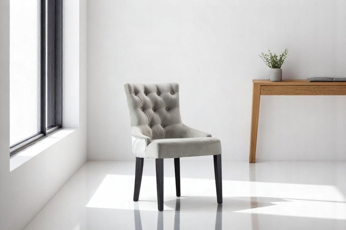 alt="Modern grey lounge chair featuring a button-cushioned seat and contrasting black legs"