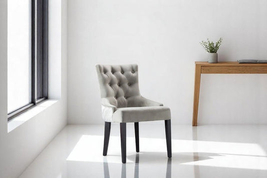 alt="Modern grey lounge chair featuring a button-cushioned seat and contrasting black legs"