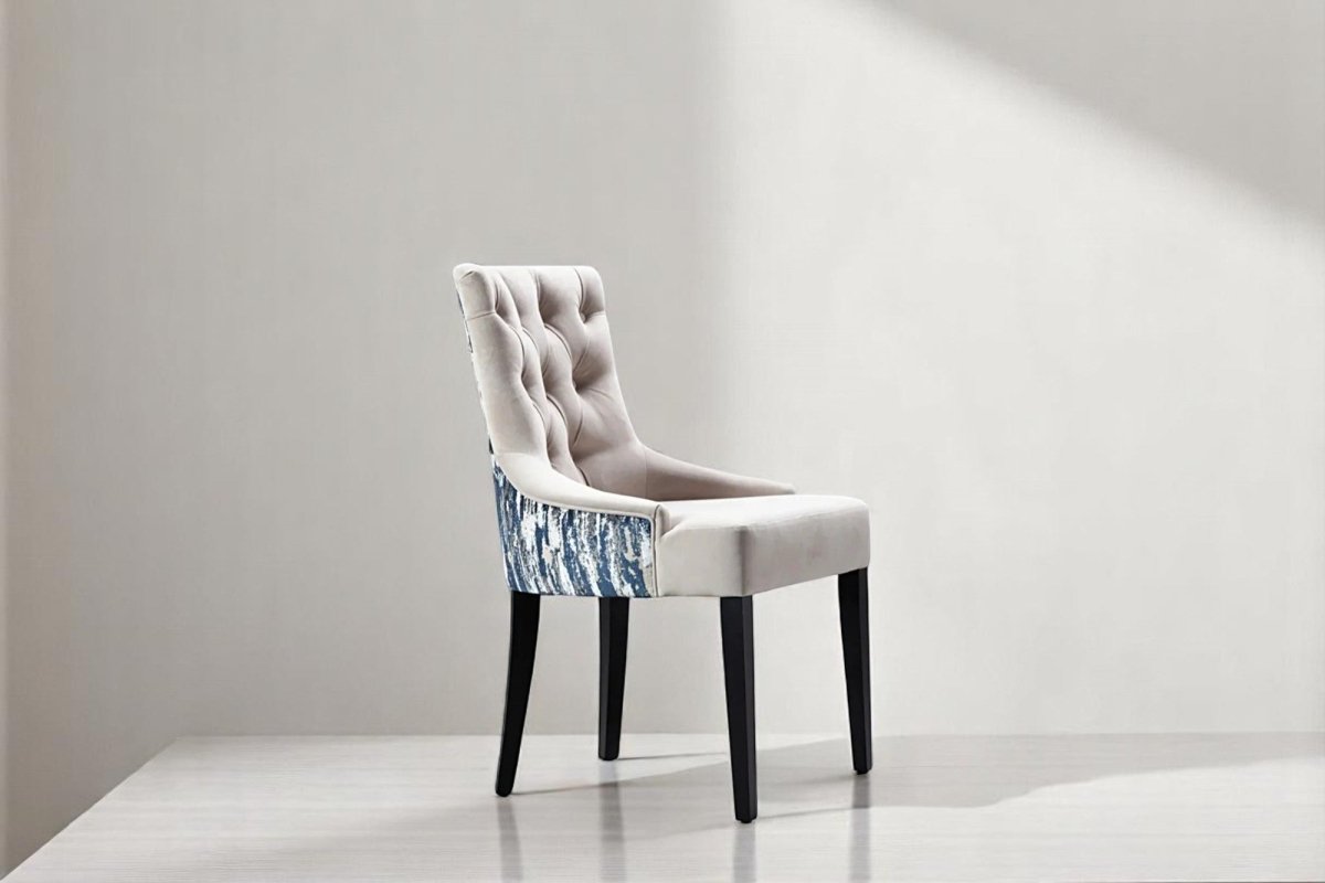 alt="Comfortable grey lounge chair with button detailing on the cushion and black wooden legs"