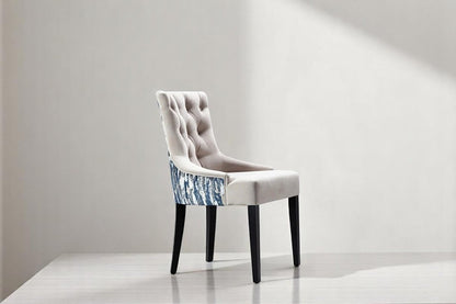 alt="Comfortable grey lounge chair with button detailing on the cushion and black wooden legs"