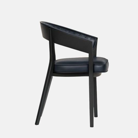 Elegant dining chair with a curved open back, featuring navy blue quilted leather upholstery and a cushioned seat, supported by a sleek black wooden frame and legs, set against a light grey background