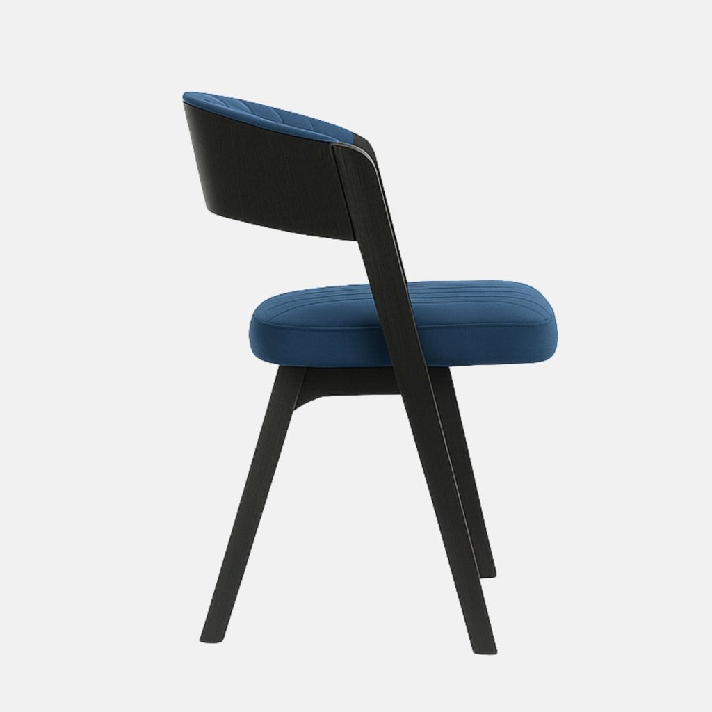 Modern dining chair with a curved open-back design, upholstered in blue fabric with vertical stitching, and supported by a black wooden frame and legs, set against a light grey background