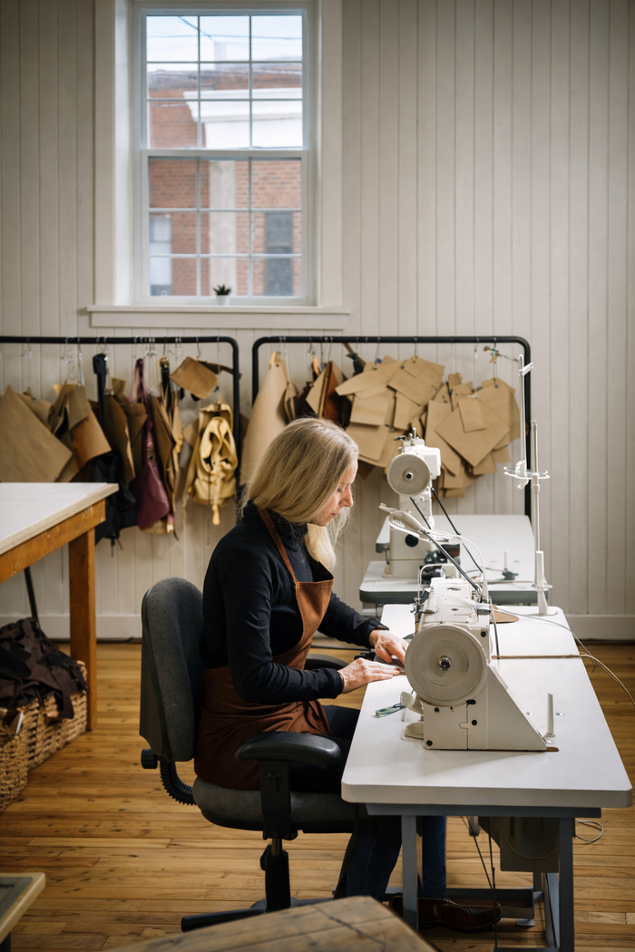 Craftsperson sewing upholstery fabric on an industrial sewing machine in a workshop