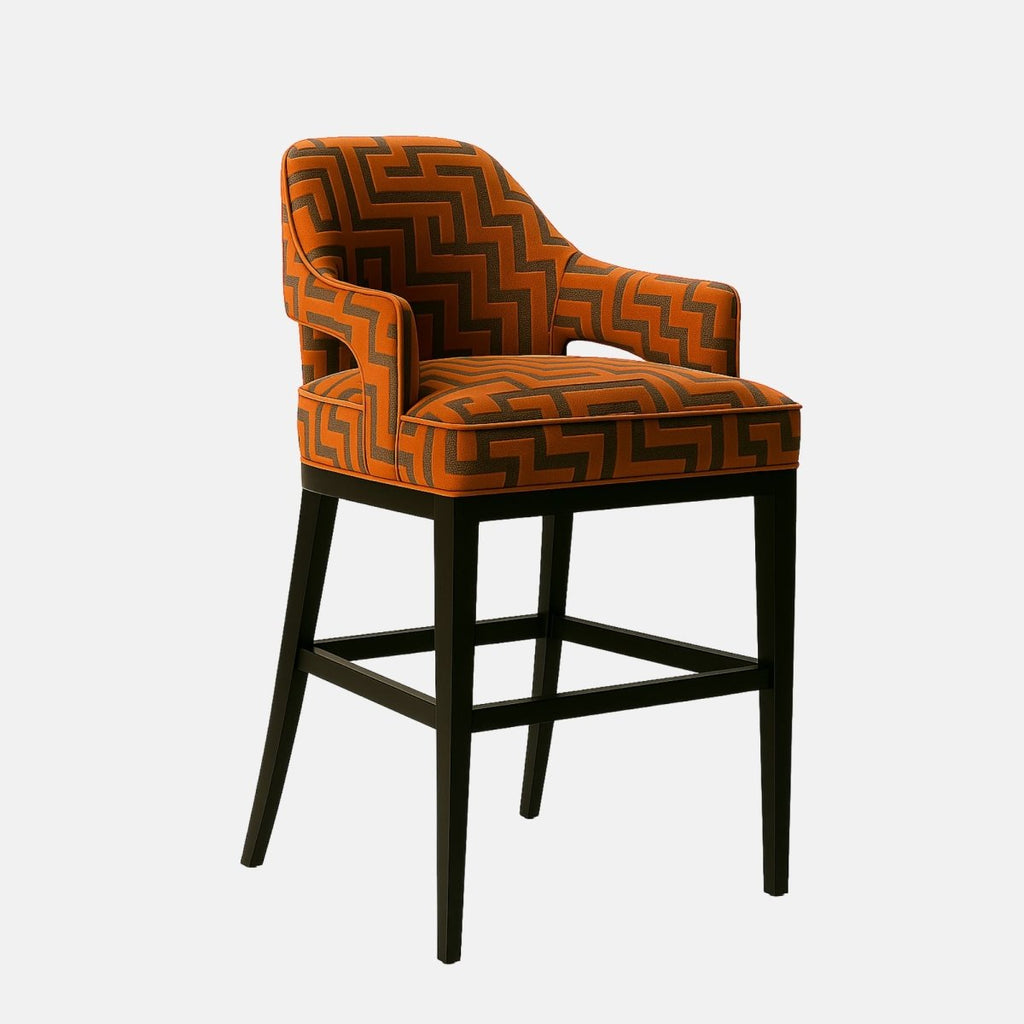 Modern bar stool with a curved backrest and arm design, upholstered in orange fabric with a bold geometric zigzag pattern. The seat is plush and supported by a sleek black wooden frame, combining contemporary style with comfort.