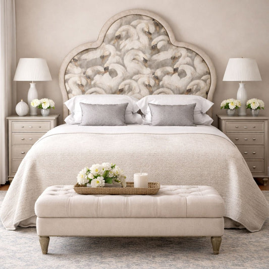 Elegant bedroom with an arched upholstered headboard featuring a swan pattern, styled with neutral bedding, matching bedside tables, and soft decorative accents.