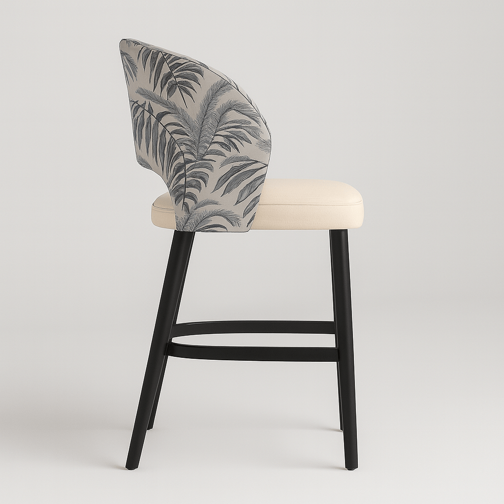 Side view of a contemporary barstool with tropical leaf-patterned upholstery, cream upholstered seat cushion, curved backrest, black wooden legs, and integrated footrest modern furniture design, neutral colour palette, stylish bar seating.