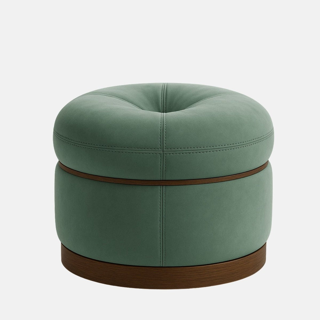 Round upholstered ottoman with a tufted top in soft sage green fabric, accented by visible stitching and a dark wooden base. The design is modern and elegant with a smooth, cushioned finish